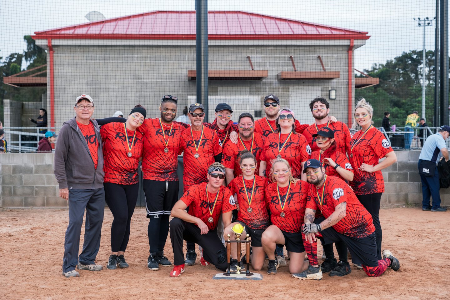 Sports team in red jerseys celebrates with a trophy on the field.